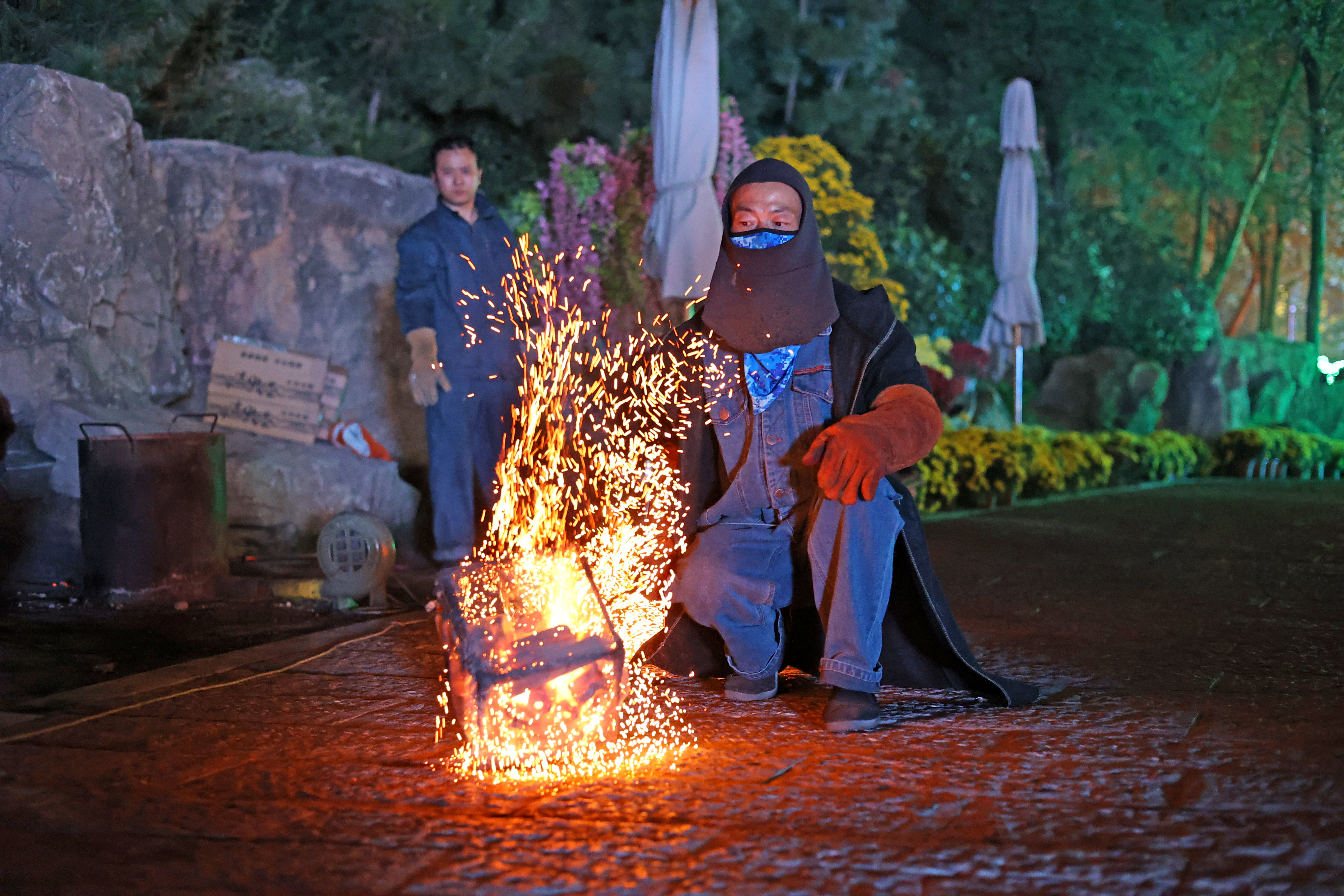 夜色如墨，炭火微微跳动，一场独特的非遗火壶表演在开封万岁山武侠城景区启幕——表演者将烧好的木炭放入火壶中，上下抖动火壶，木炭撞击壶体周围的铁网，喷撒出漫天火星，犹如星河落人间。观众屏息凝神，目睹这场视觉盛宴。全媒体记者 袁洋 摄