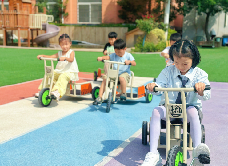 幼儿园户外场地，几个孩子兴致勃勃骑着三轮小车，在多彩地面上享受欢乐时光。
       全媒体记者 李水龙文/图