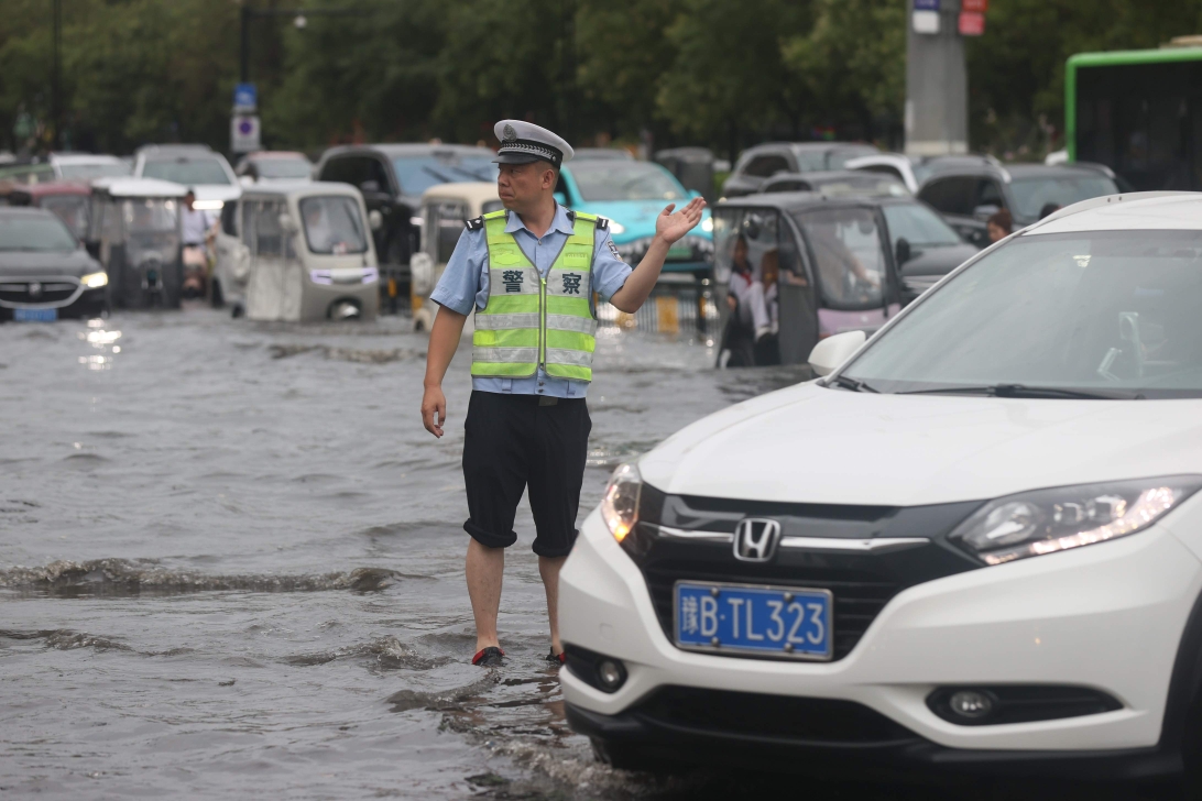 7月15日早晨，一场突如其来的大雨为市民出行带来诸多不便，市交警支队民警冒雨指挥交通，确保市民安全有序通行。全媒体记者 刘睿恒 摄