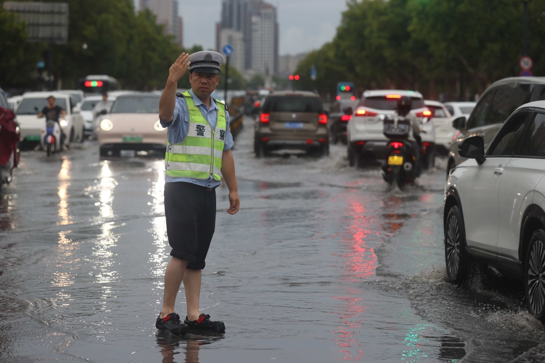 7月15日早晨，一场突如其来的大雨为市民出行带来诸多不便，市交警支队民警冒雨指挥交通，确保市民安全有序通行。全媒体记者 刘睿恒 摄